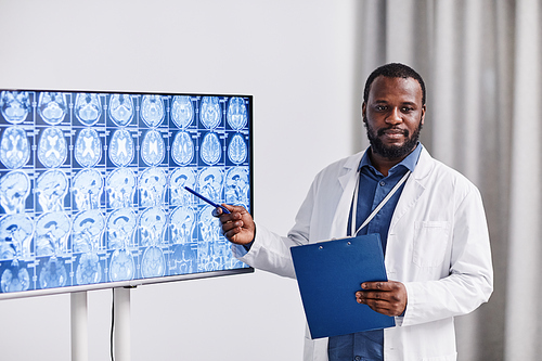 Young confident African-American medical officer pointing at brain scan while making presentation to colleagues and consulting with them