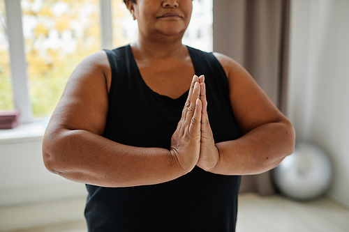 Close up of black senior woman meditating while doing yoga indoors, focus on hands in balance