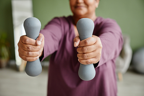 Close up of black senior woman holding dumbbells and enjoying workout at home, copy space