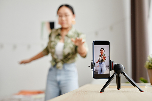 Background image of Asian teenage girl filming video for social media at home, focus on smartphone screen, copy space