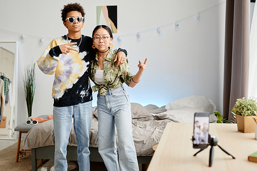 Portrait of two gen Z teenagers filming video for social media, boy and girl posing for smartphone recording, copy space