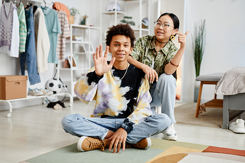 Full length portrait of two gen Z teenagers boy and girl smiling at camera while posing in home interior, copy space
