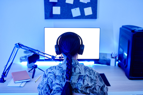 Back view of teenage girl recording podcast at night with blue neon lighting, copy space