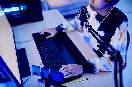 High angle closeup of teenage boy playing video games at night in room with blue neon lighting, copy space