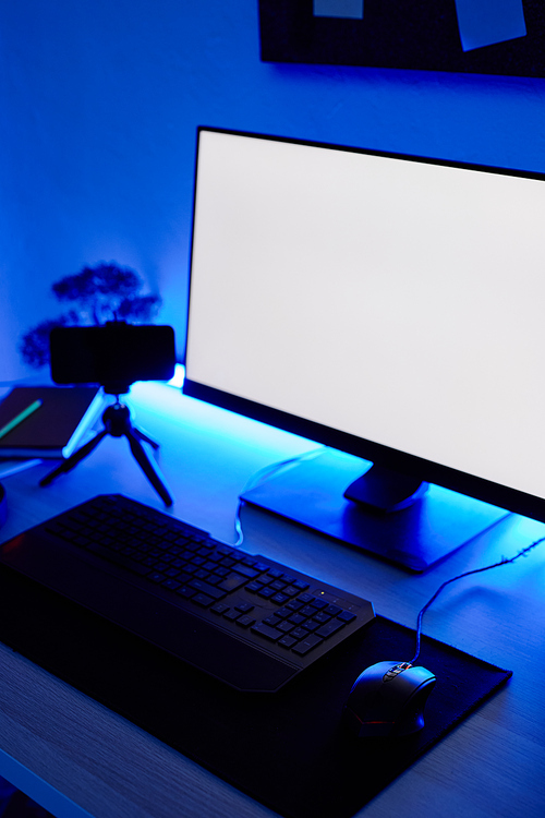 Vertical background image of gaming setup PC on desk lit with blue neon lighting, screen mockup