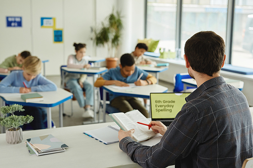 Rear view of teacher with group of kids in school classroom, copy space