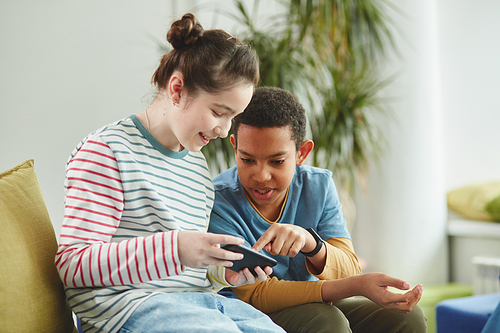 Portrait of two kids boy and girl using smartphone in school during break both dressed in colorful clothes