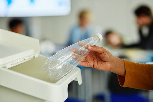 Closeup of unrecognizable child using using waste sorting bins in school and putting plastic bottle in for recycling, copy space