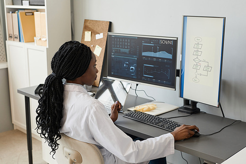Portrait of black female engineer at workplace programming algorithms, copy space