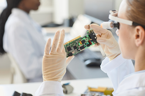 Close up of female engineer inspecting electronic parts in laboratory, copy space