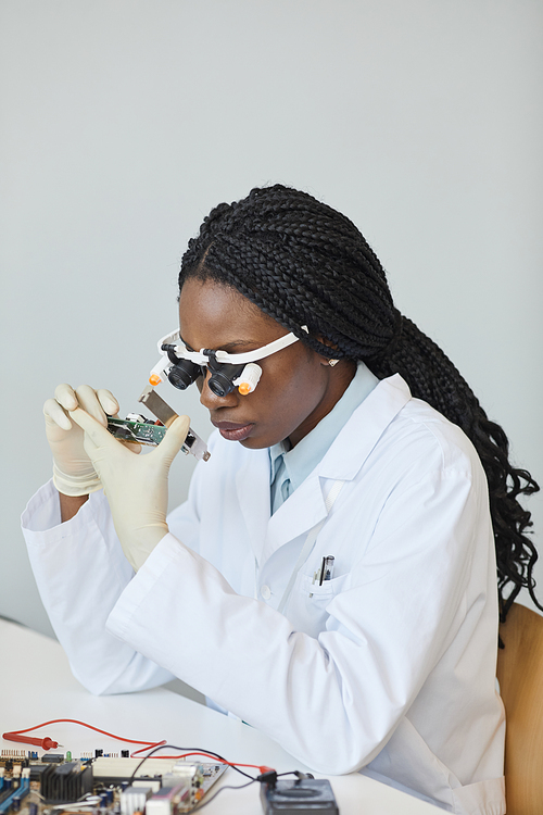 Minimal portrait of black female engineer inspecting electronic parts in laboratory