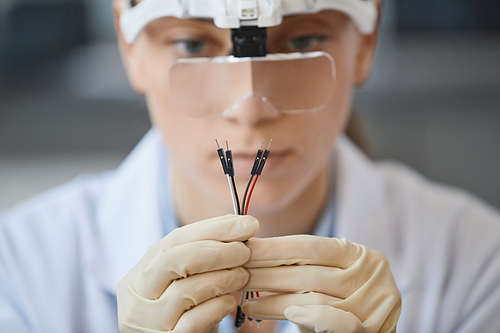 Close up of female engineer holding wires in lab with blurred background, copy space