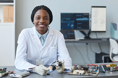 Portrait of smiling black woman as female engineer looking at camera in laboratory, copy space