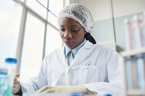 Low angle portrait of young black woman working in medical laboratory, copy space