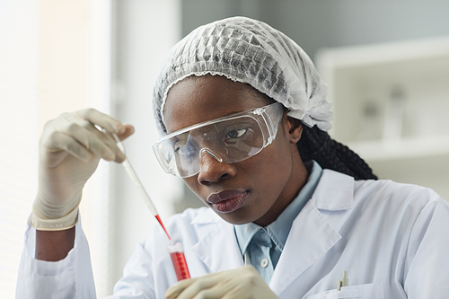 Portrait of young black woman wearing protective glasses while working in medical laboratory