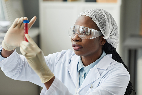 Portrait of young black woman holding test tube while working in science laboratory
