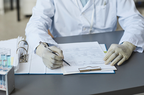 Close up of female medical scientist filling in charts in laboratory, copy space