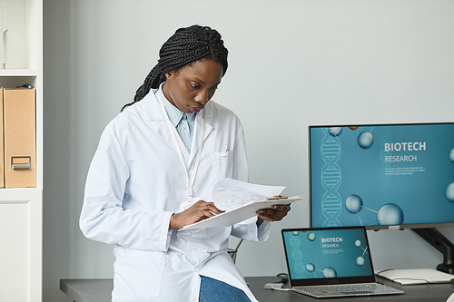 Portrait of young black woman working in research laboratory with computers in background, copy space