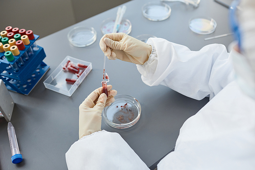 Side view portrait of woman wearing full protective gear while analyzing blood tests in laboratory, copy space