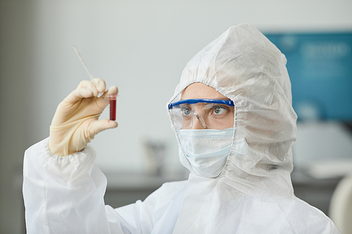 Side view portrait of two people wearing full protective gear analyzing blood samples in medical laboratory