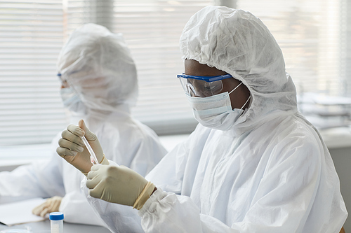 Portrait of young female scientist wearing full protective gear while performing research with hazardous samples in medical laboratory, copy space