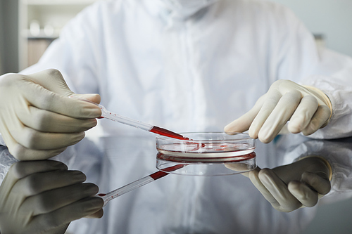 High angle view of scientist wearing full protective gear while performing blood test in petri dish at medical lab