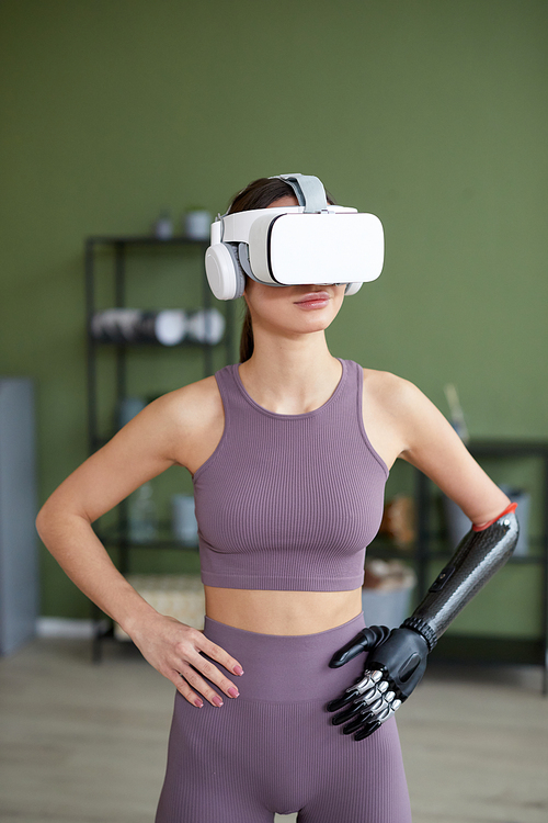 Young girl in sports clothing doing exercises at home in virtual reality glasses