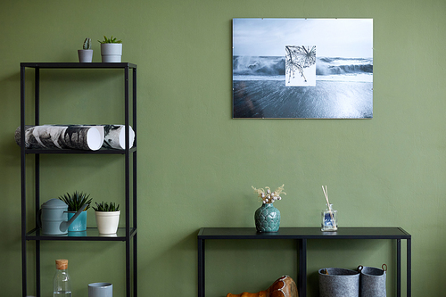 Horizontal image of domestic room with modern painting on green wall and shelves with design objects