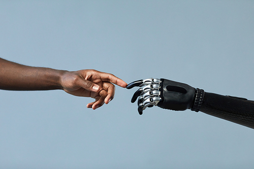 Close-up of African man and woman with prosthetic arm touching fingers against blue background