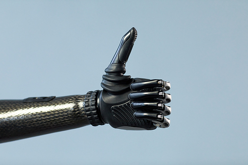 Close-up of woman with prosthetic arm showing thumb up isolated on blue background