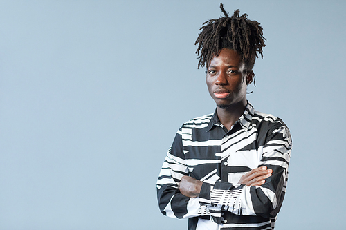 Portrait of African young confident man with fashion hairstyle looking at camera on blue background