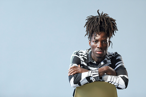 Portrait of African guy with stylish hairstyle looking at camera isolated on blue background