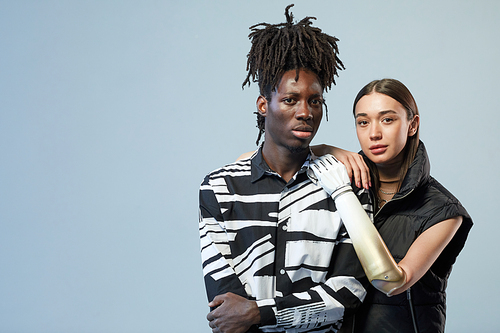 Portrait of multiethnic young couple looking at camera standing against blue background