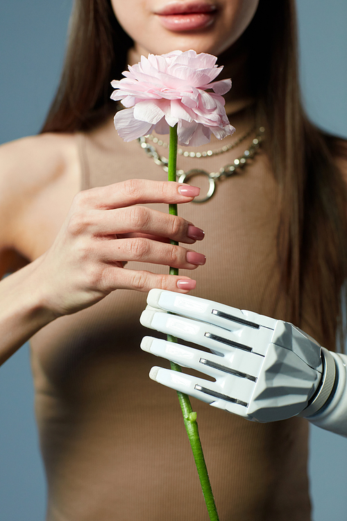 Close-up of young girl with disability holding beautiful flower in her hands against blue background