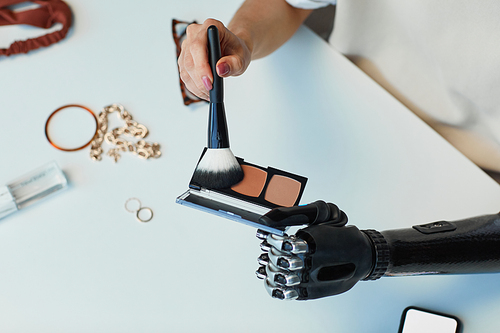 High angle view of girl with prosthetic arm using brush to apply blush