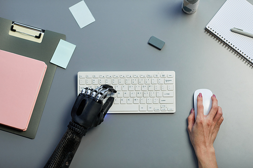 High angle view of woman with disability typing on wireless computer keyboard at table