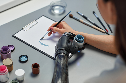 Close-up of young woman learning to paint with paints at table