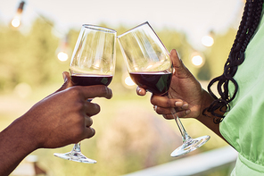 Close up of black young couple toasting and enjoying glass of wine at terrace during romantic date outdoors in Summer