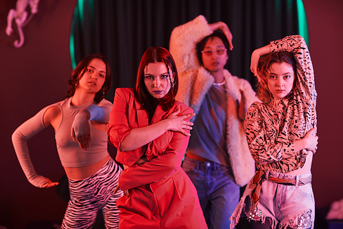 Group of girls in vogue dance crew posing in studio with red neon light
