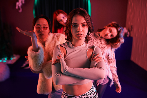 Waist up portrait of vogue dance crew posing in pink neon light, focus on young girl in foreground