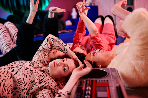 Closeup of vogue dance crew lying on floor in red neon light focus on gril with glitter makeup looking at camera