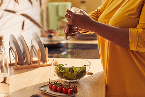 Closeup of overweight black woman cooking healthy meal in kitchen lit by sunlight, copy space