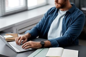 Close-up of young man typing on laptop keyboard while sitting by desk and searching online information or carrying out assignment