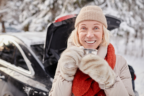 Portrait of smiling mature woman enjoying cup of hot coco outdoors in winter and looking at camera, copy space