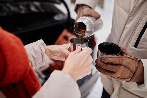 Close up of unrecognizable mature couple enjoying cup of hot coco outdoors in winter