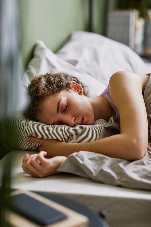 Tired young woman sleeping in her comfortable bed in bedroom