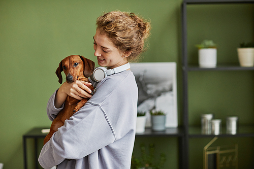 Happy young girl playing with her lovely dog during leisure time at home