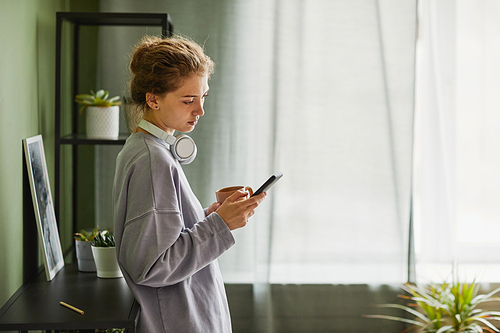 Young girl listening to music and drinking coffee in the morning at home