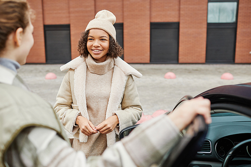 African young girl smiling and talking to her friend while they meeting in the city