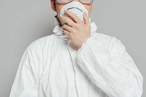 cropped view of epidemiologist in hazmat suit touching respirator mask isolated on grey